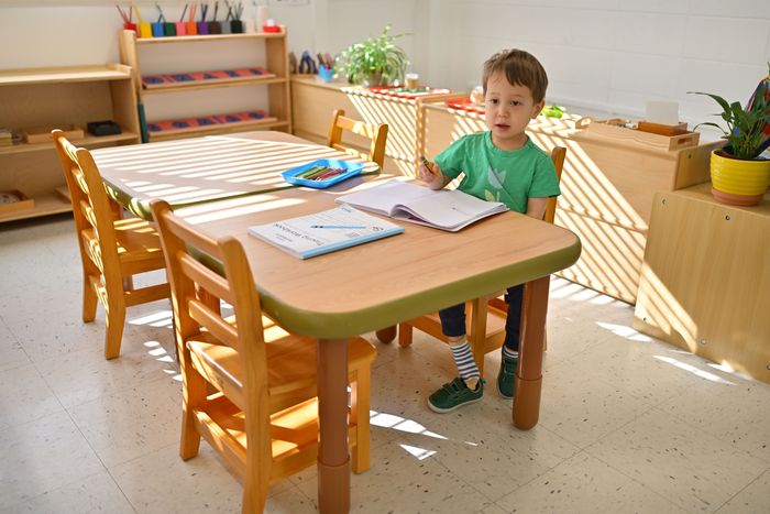 Child at Montessori work table in sunlit classroom