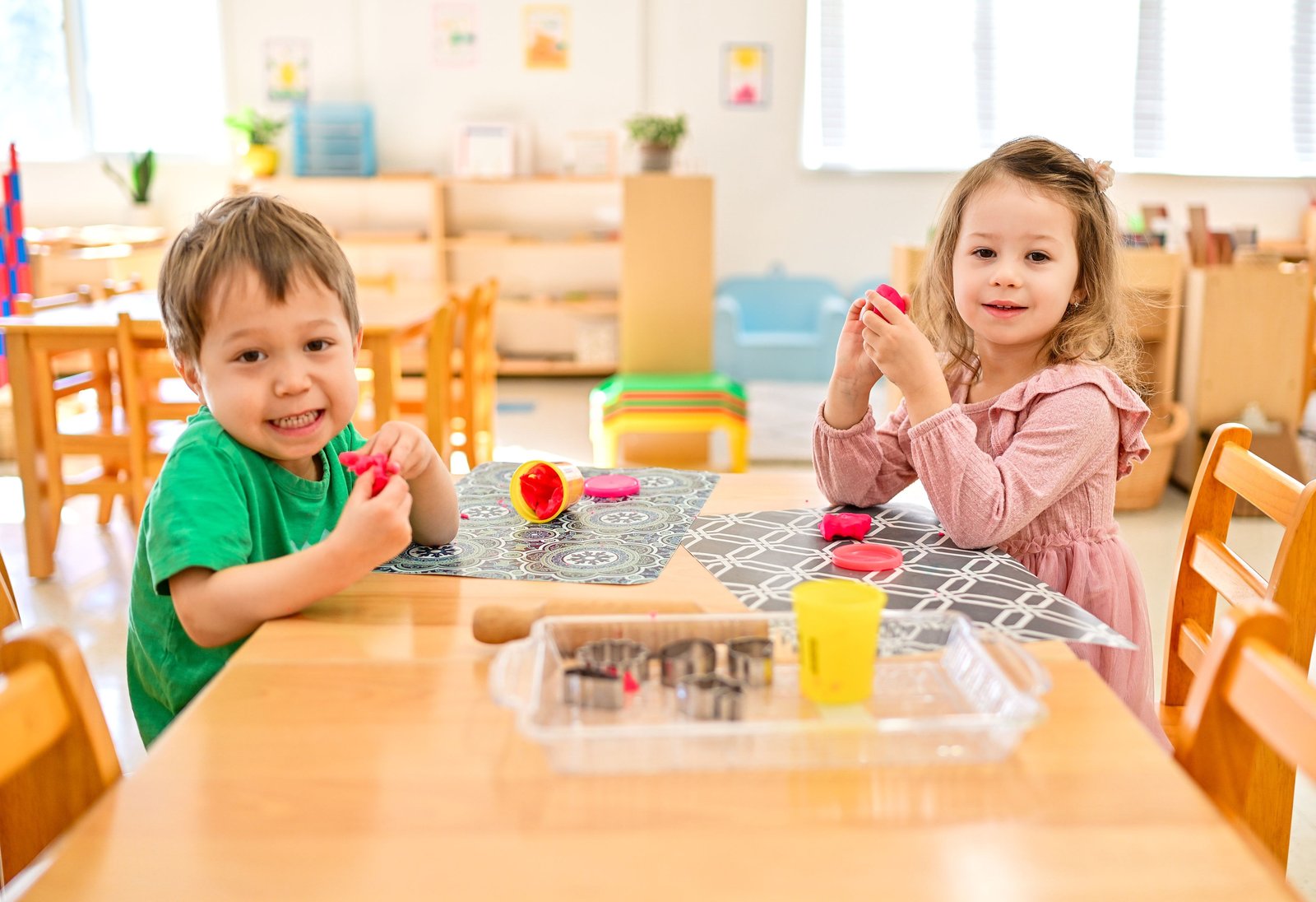 Two happy children making shapes with playdough