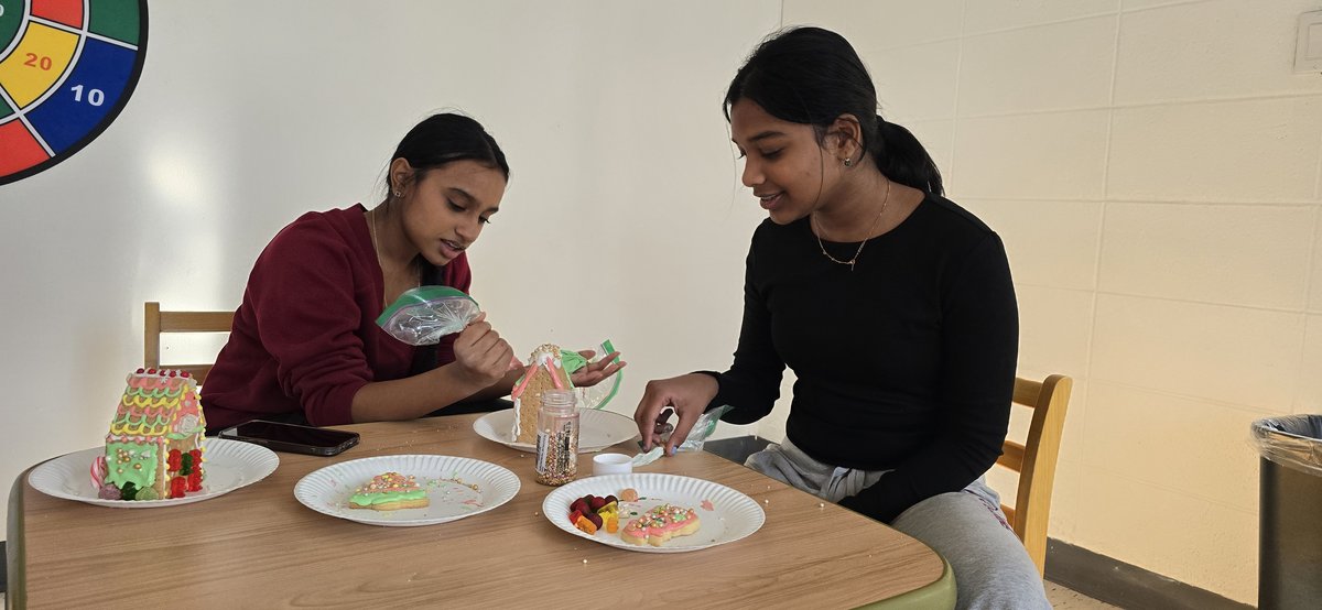 Children and parents building gingerbread houses at holiday event