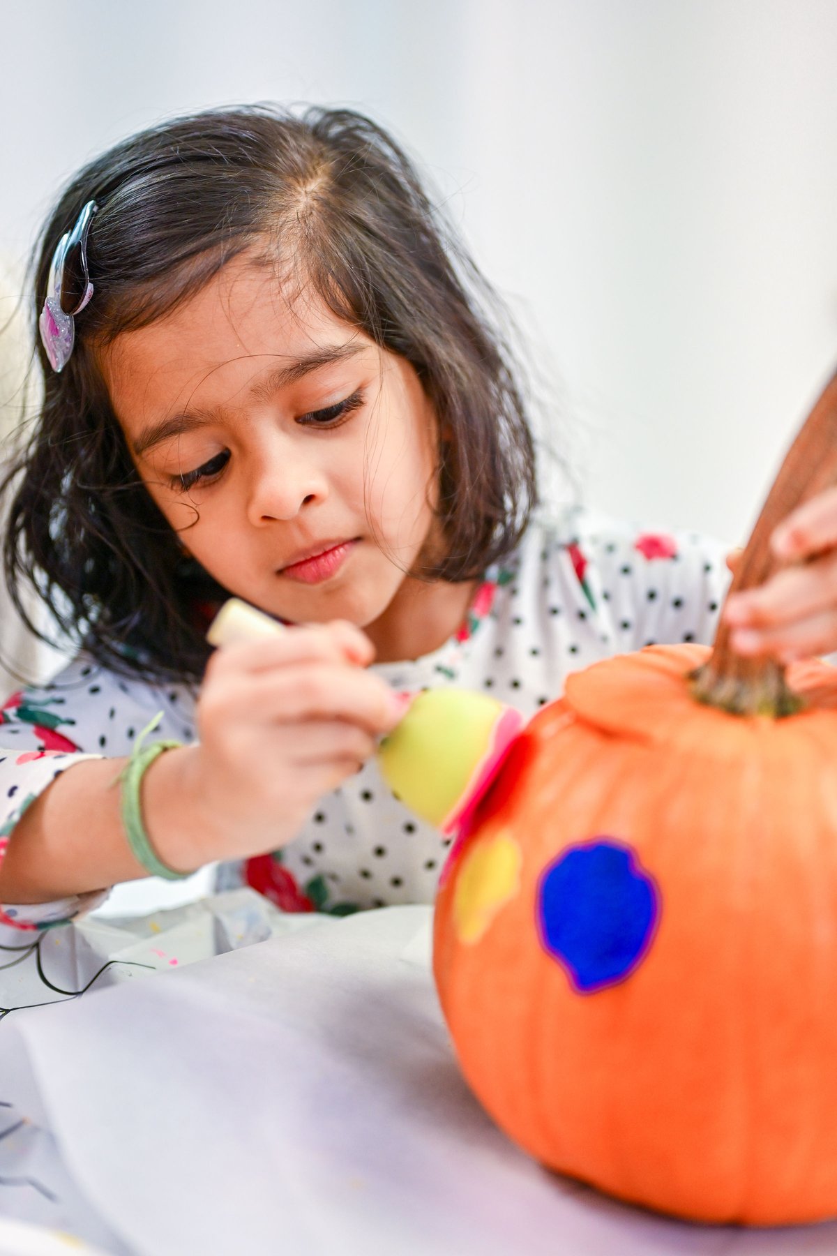 Child in costume proudly showing off Halloween pumpkin