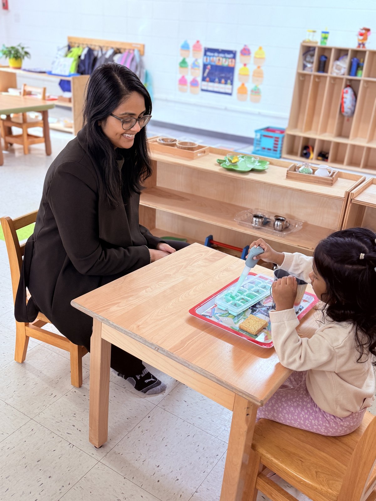 Saritha Vellore sitting with child at Montessori activity
